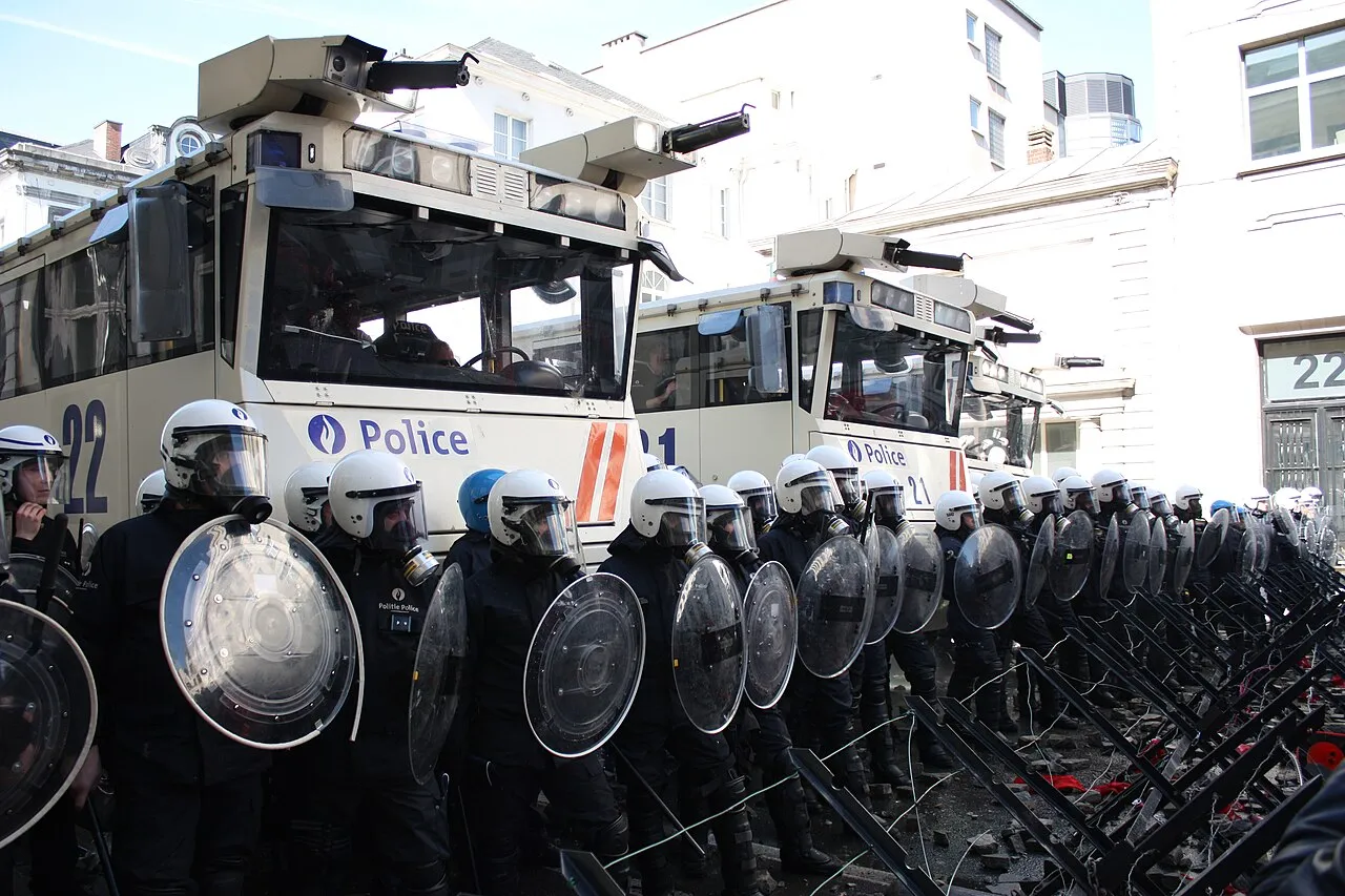 Een politielinie met oproerpolitie en brandweerwagens blokkeert een straat in Brussel tijdens een betoging.