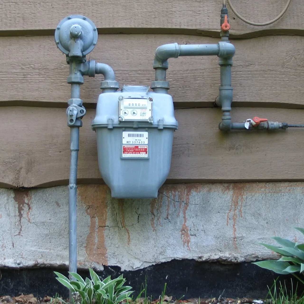 Een gasmeter bij een woning, symbool voor de energiefactuur van gezinnen